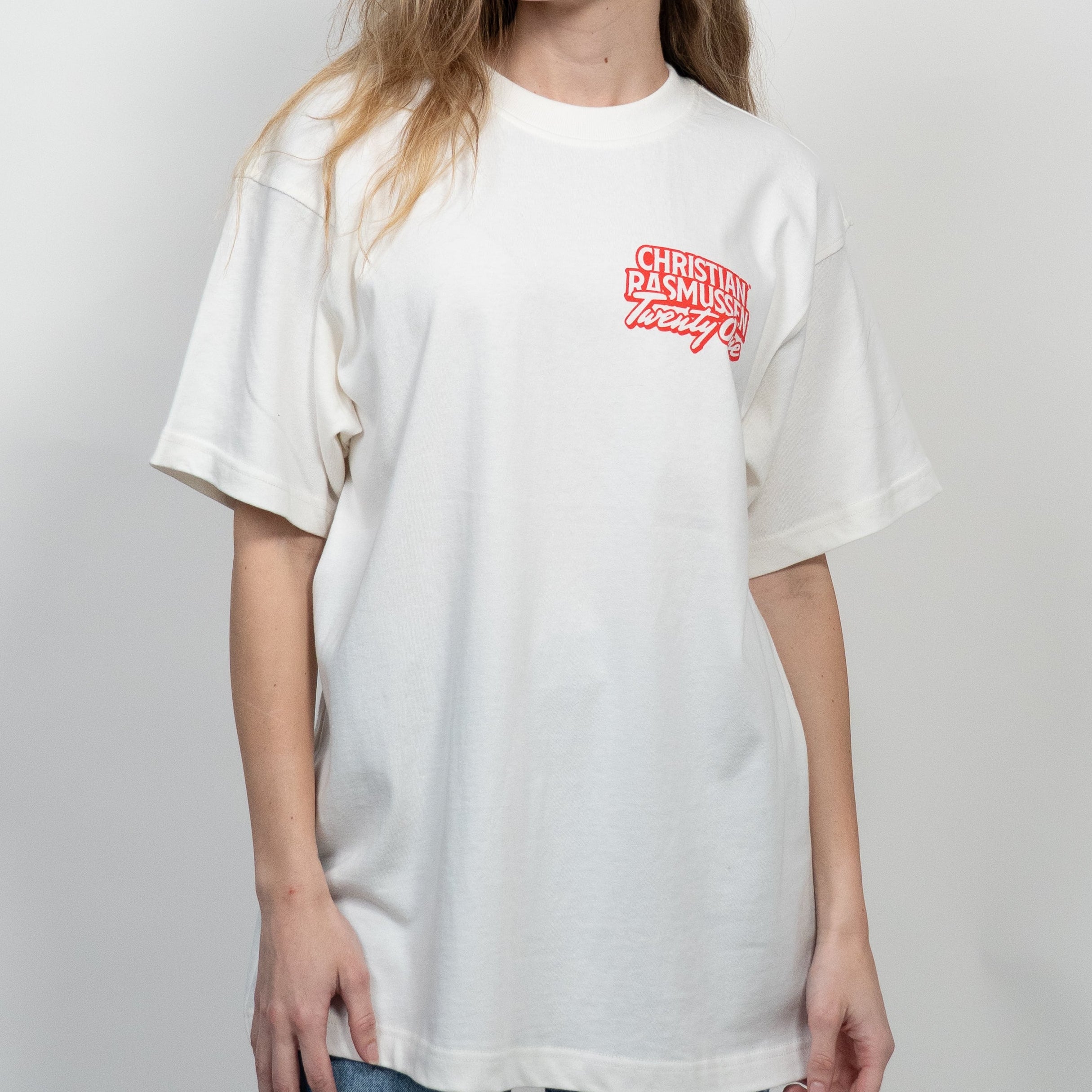 Woman wearing a white t-shirt with red text on a plain background