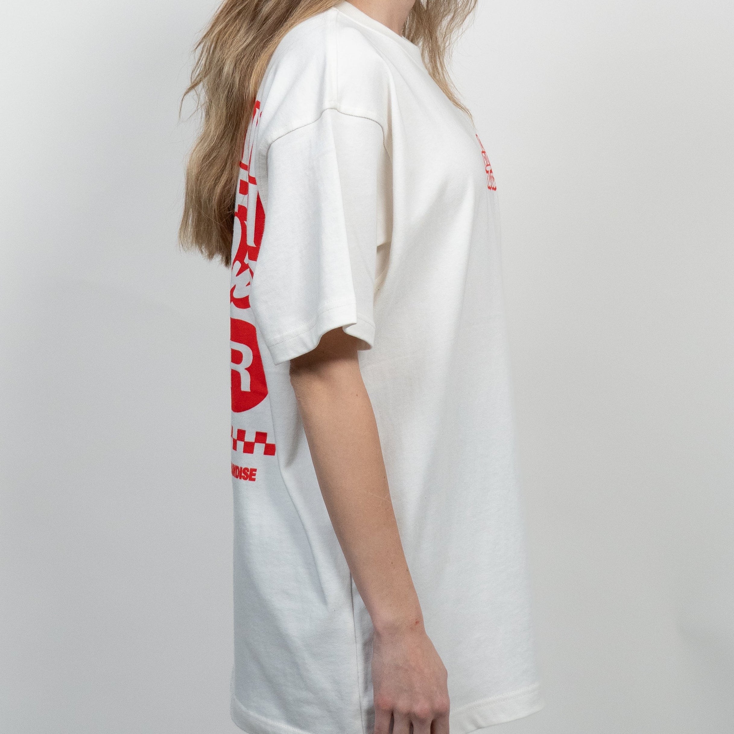 Woman wearing a white t-shirt with red text and a checkered logo on a plain background