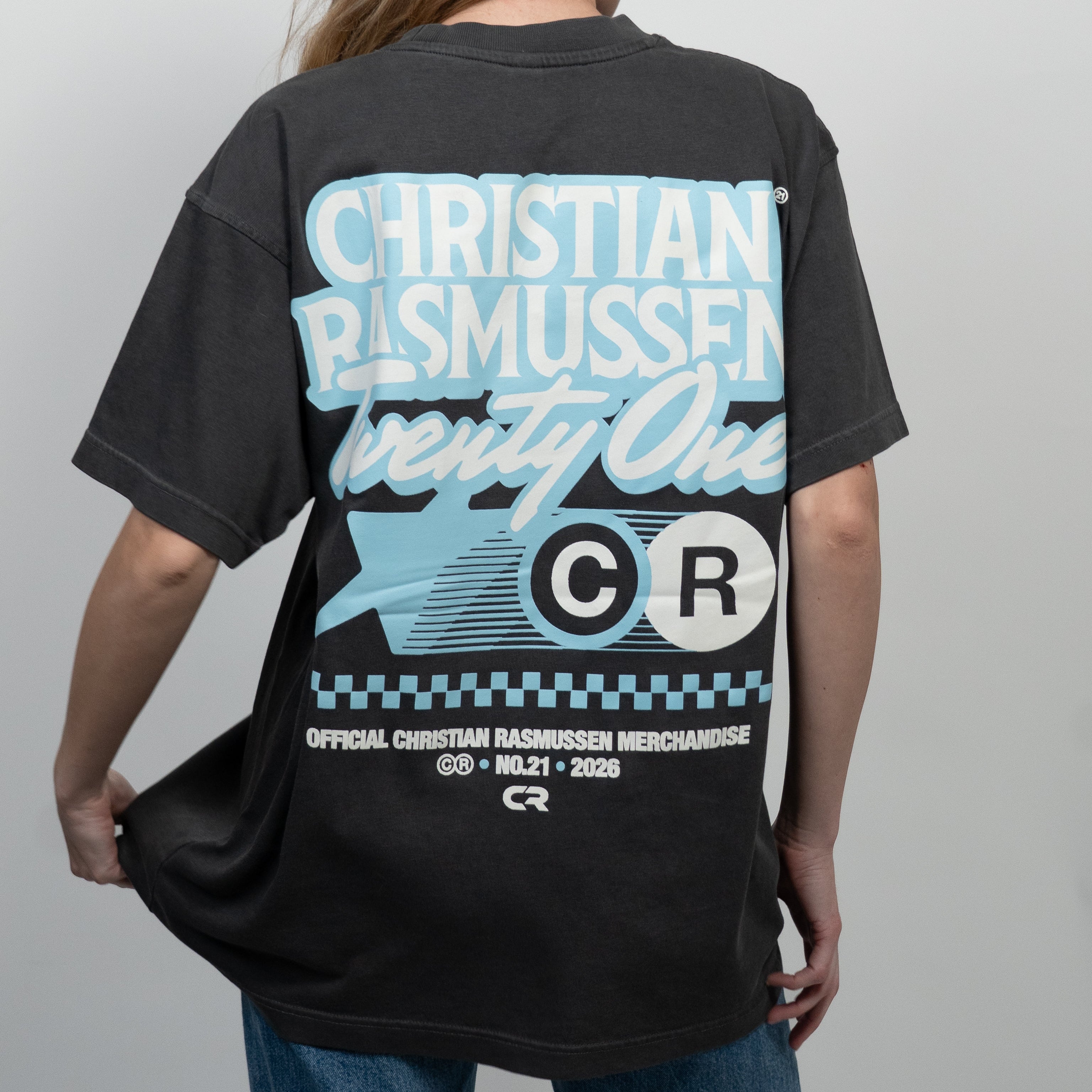 Person wearing a black t-shirt with branding on the back against a gray background