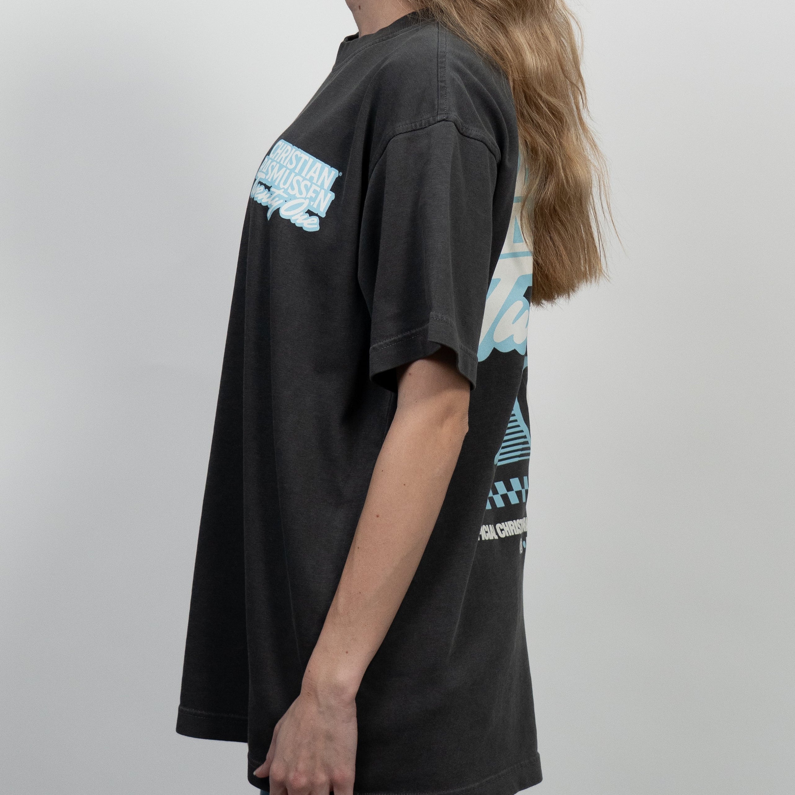 Person wearing a black t-shirt with graphic designs on a plain background