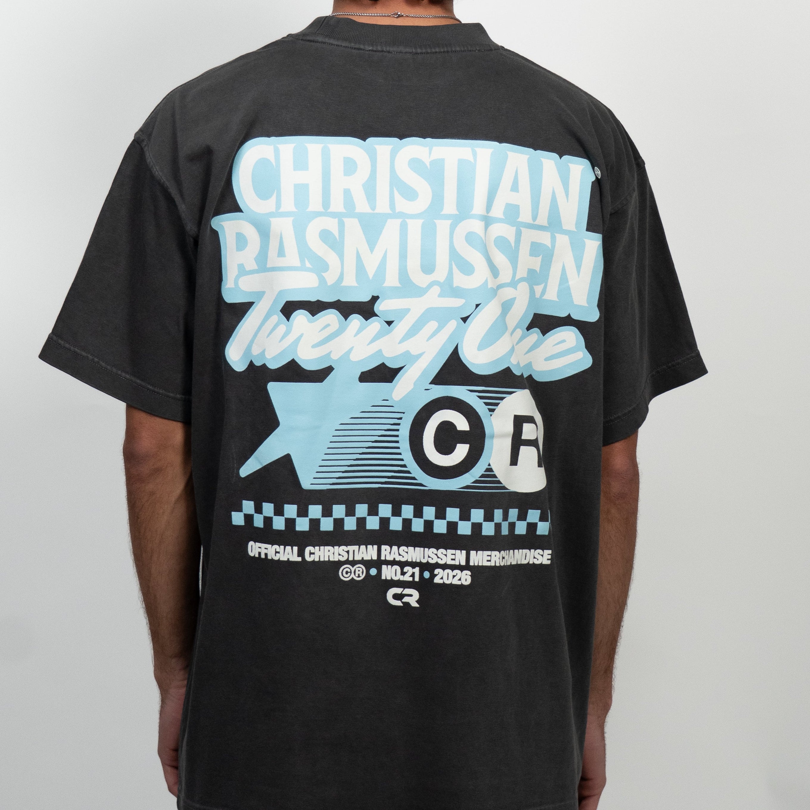 Person wearing a black t-shirt with blue and white text and graphics on the back, against a plain background.