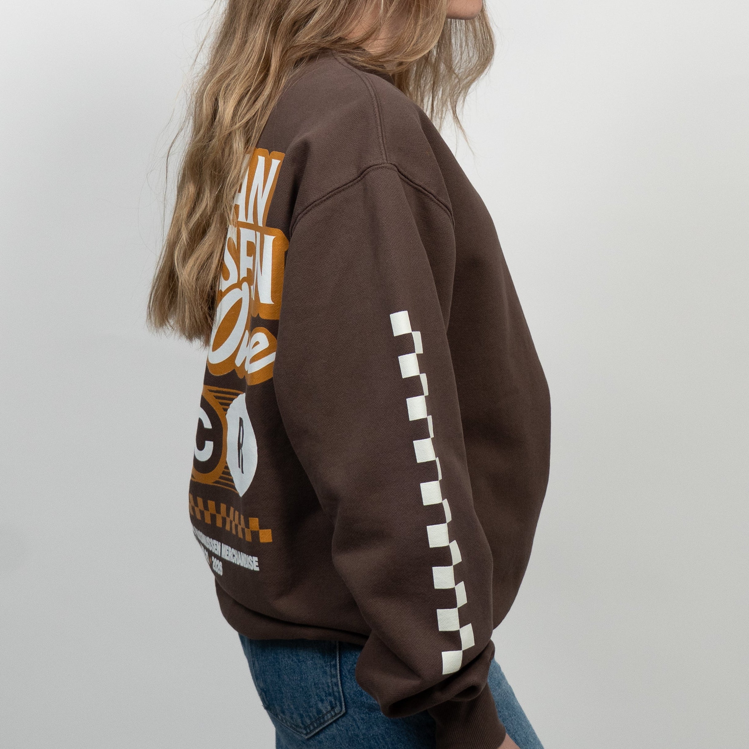 Person wearing a brown sweatshirt with text and graphics on a white background