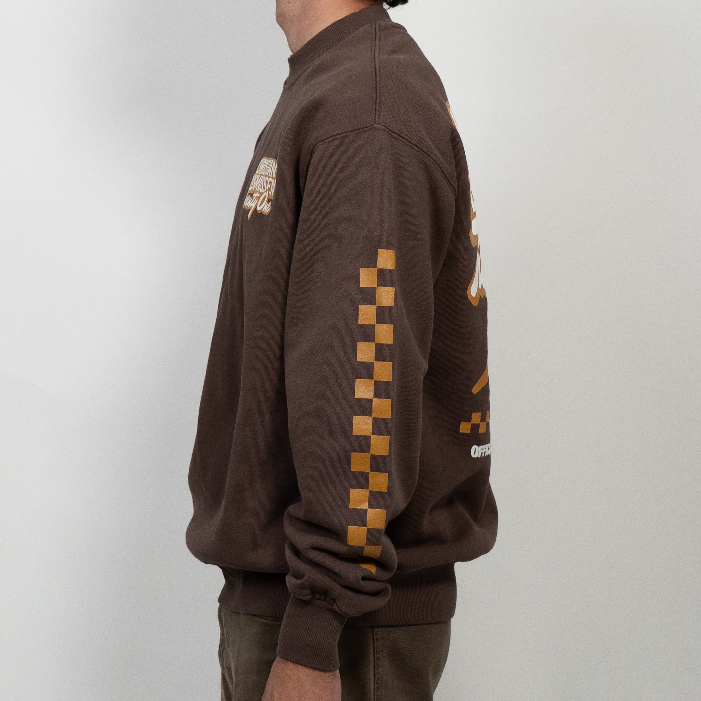 Man wearing a brown sweatshirt with checkered pattern on sleeves against a white background