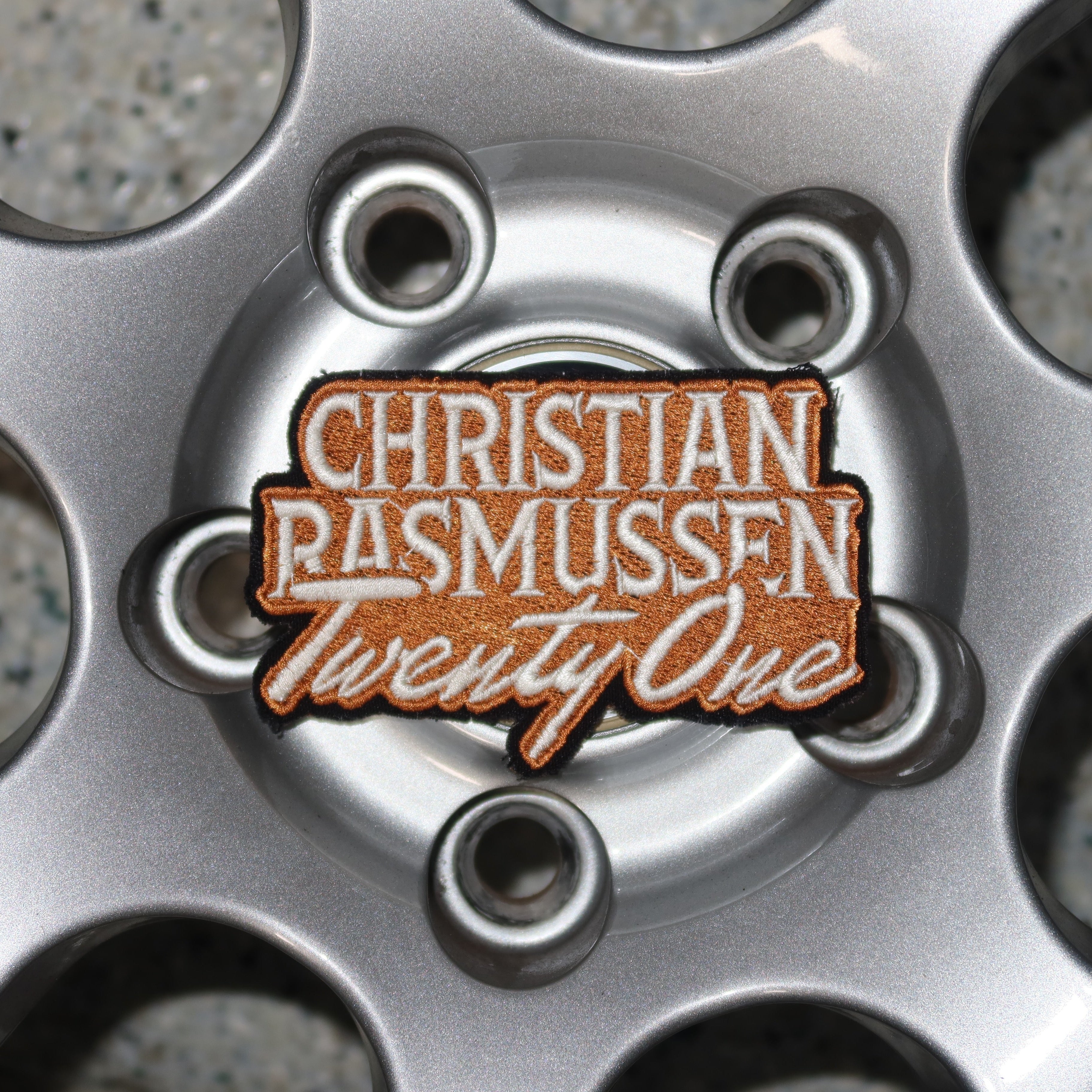 Close-up of a car wheel with a 'Christian Rasmussen Twenty One' badge.