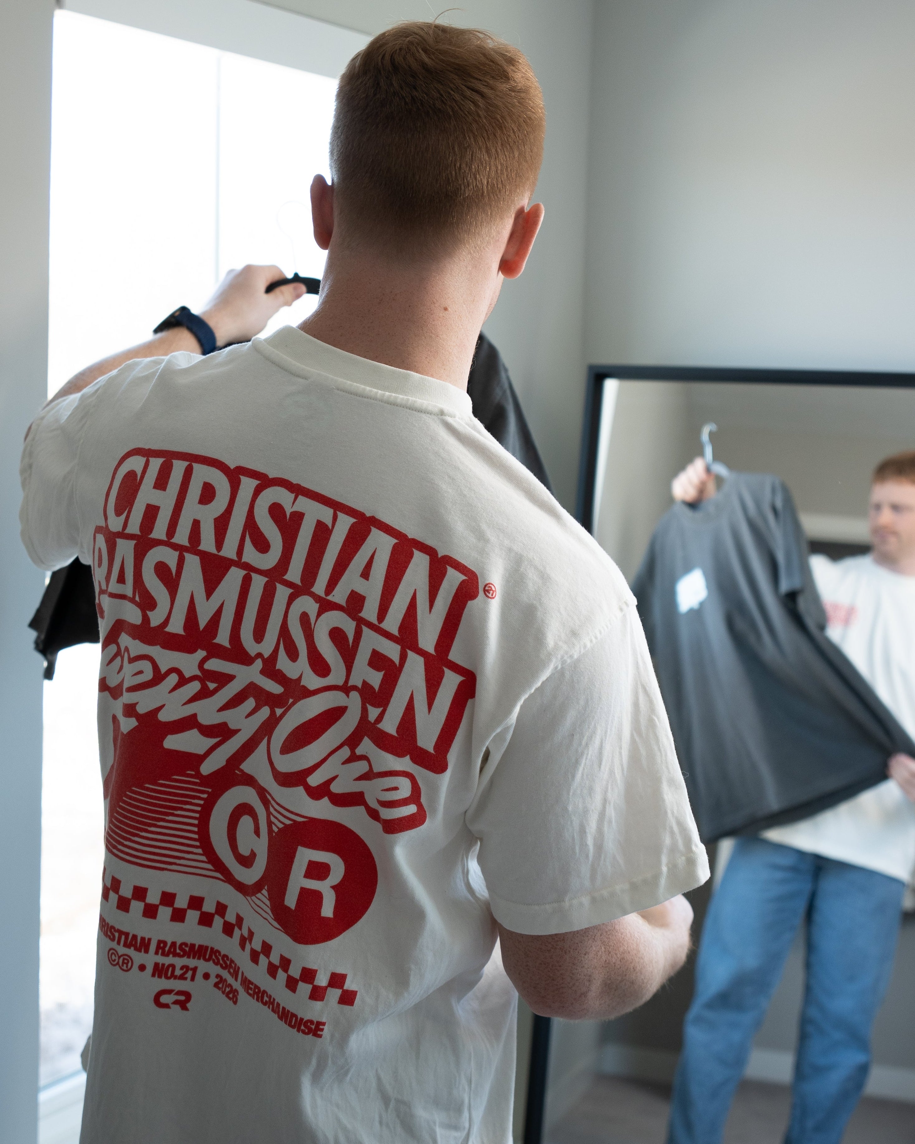 Person wearing a white t-shirt with red text in a room setting