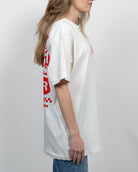 Woman wearing a white t-shirt with red text and a checkered logo on a plain background