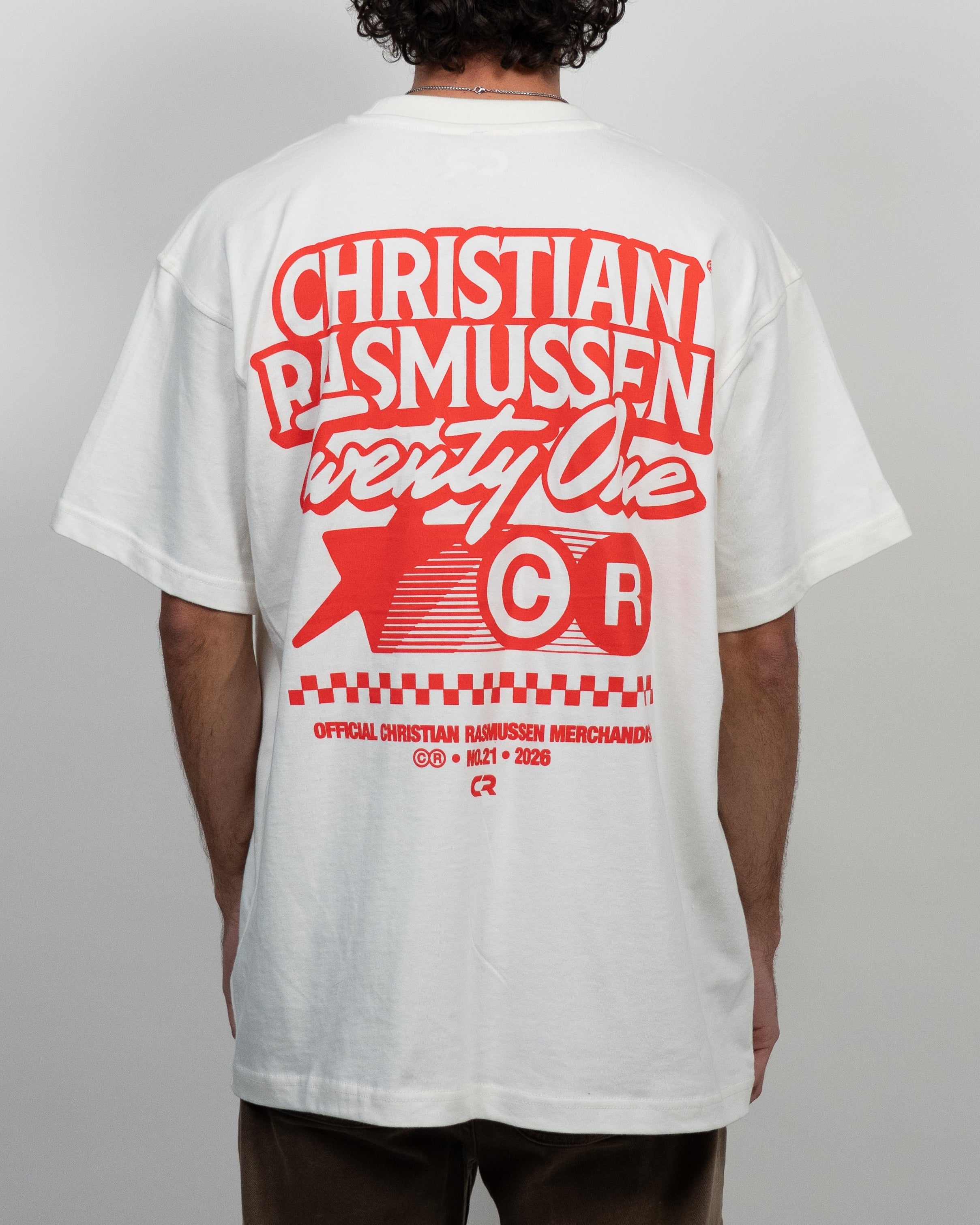 Person wearing a white t-shirt with red text and graphics on the back, standing against a plain background.