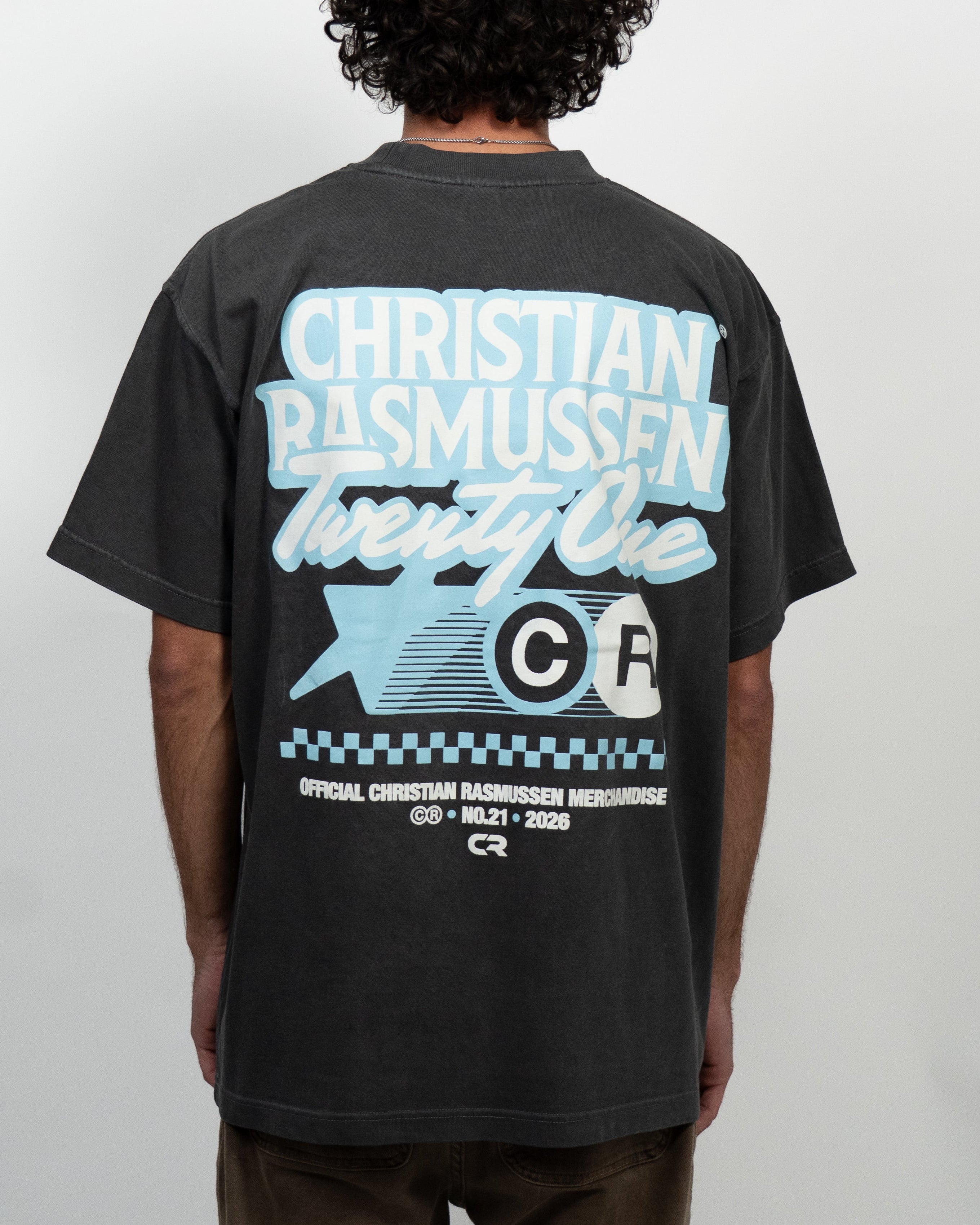 Person wearing a black t-shirt with blue and white text and graphics on the back, against a plain background.