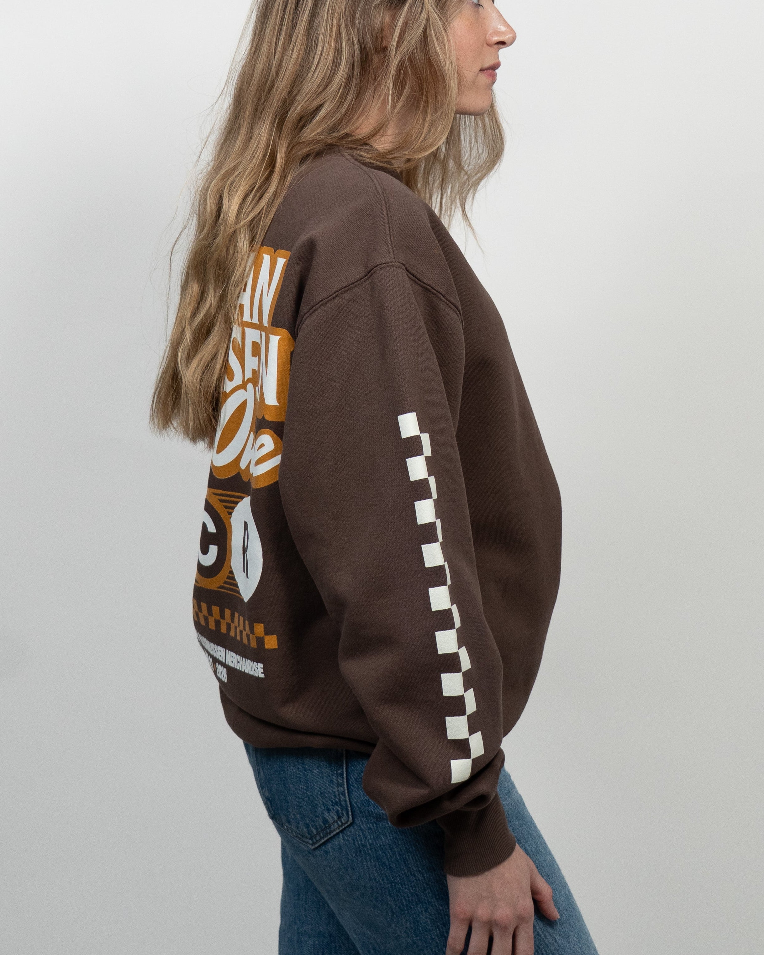 Person wearing a brown sweatshirt with text and graphics on a white background