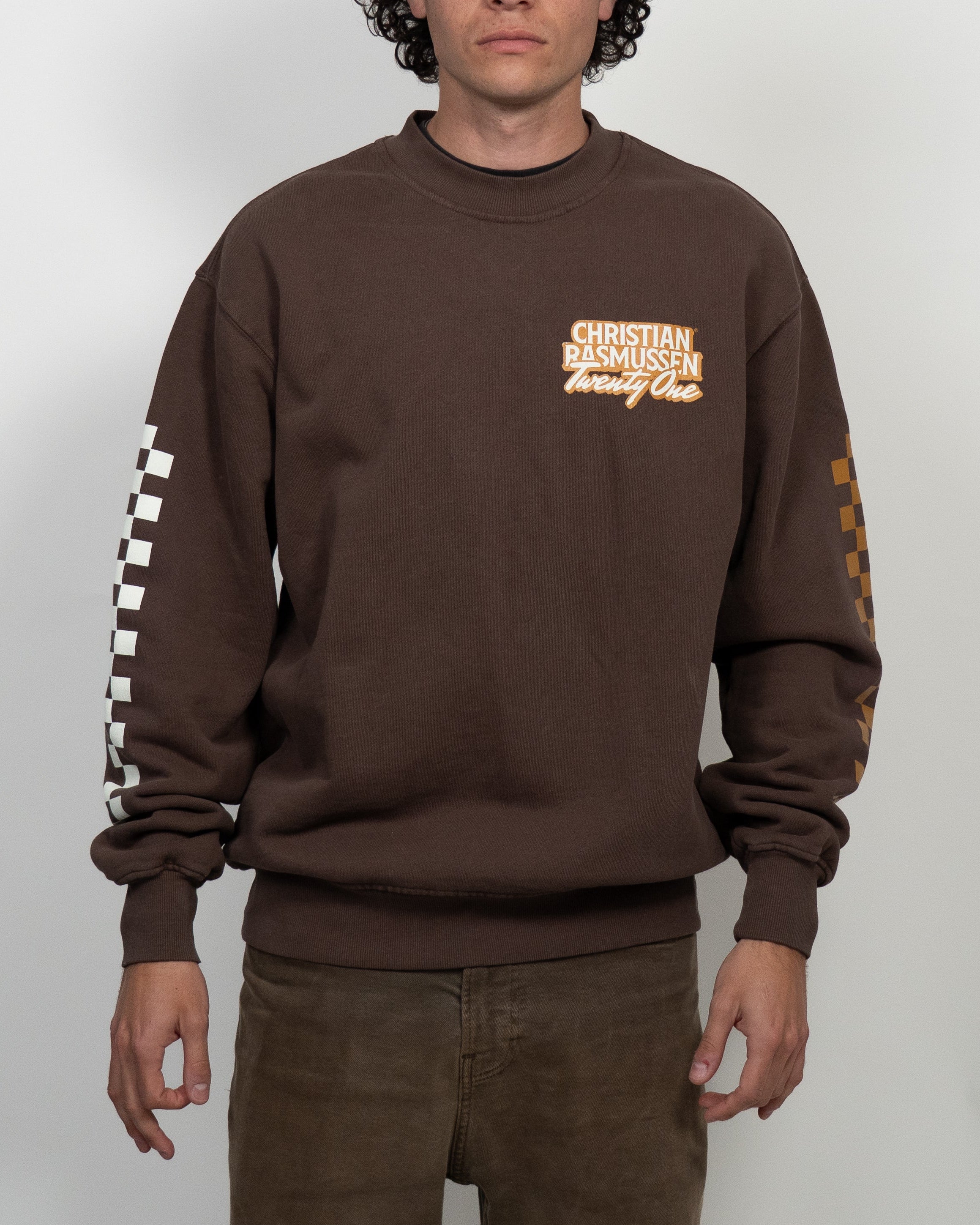 Person wearing a brown sweatshirt with visible branding on a white background
